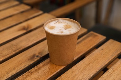 Photo of Takeaway paper cup with coffee on wooden table