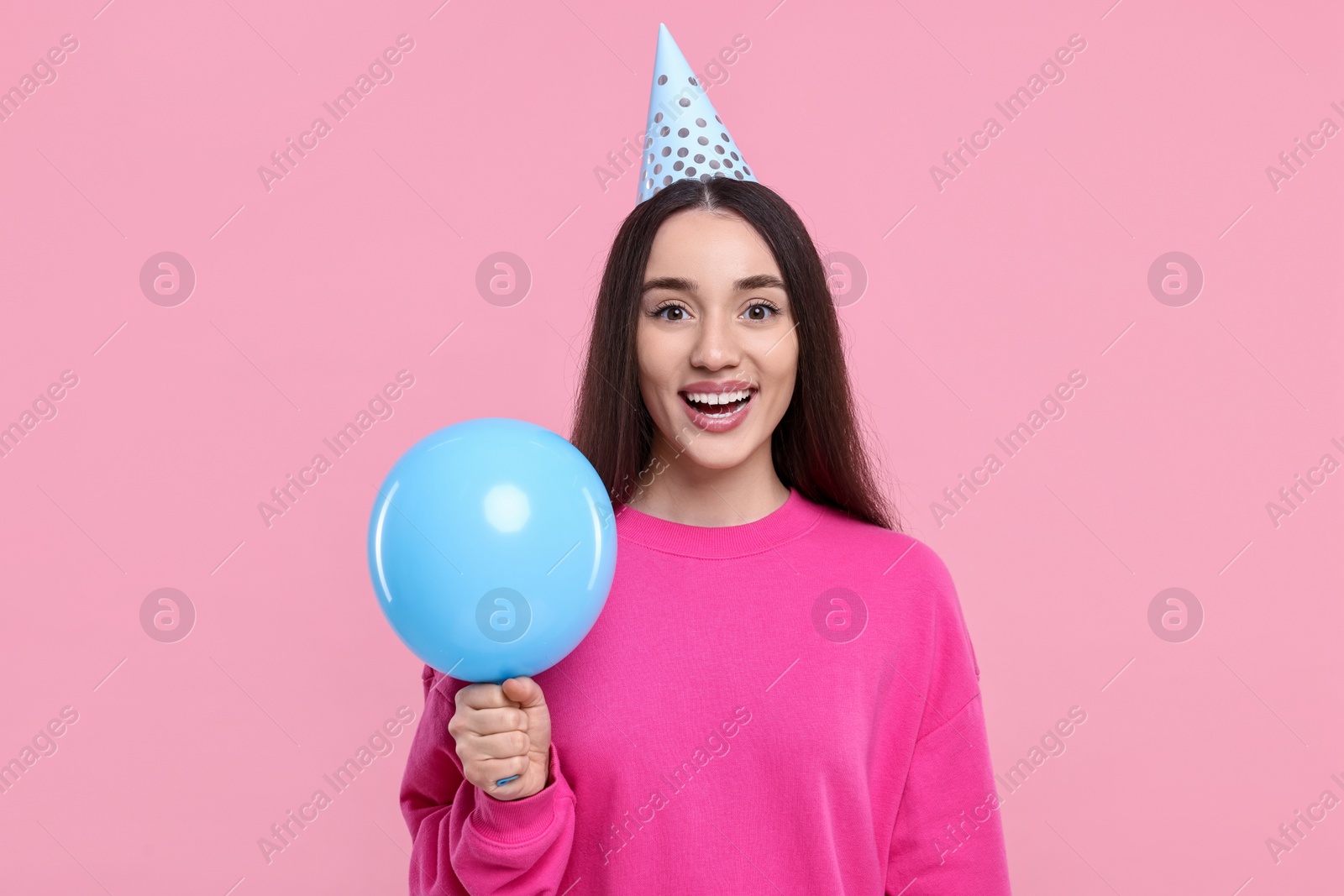 Photo of Happy woman in party hat with balloon on pink background
