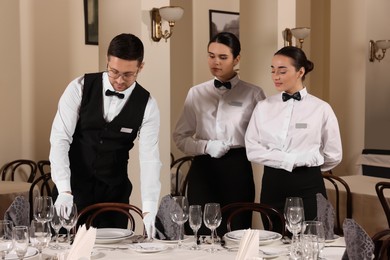 People setting table during professional butler courses in restaurant