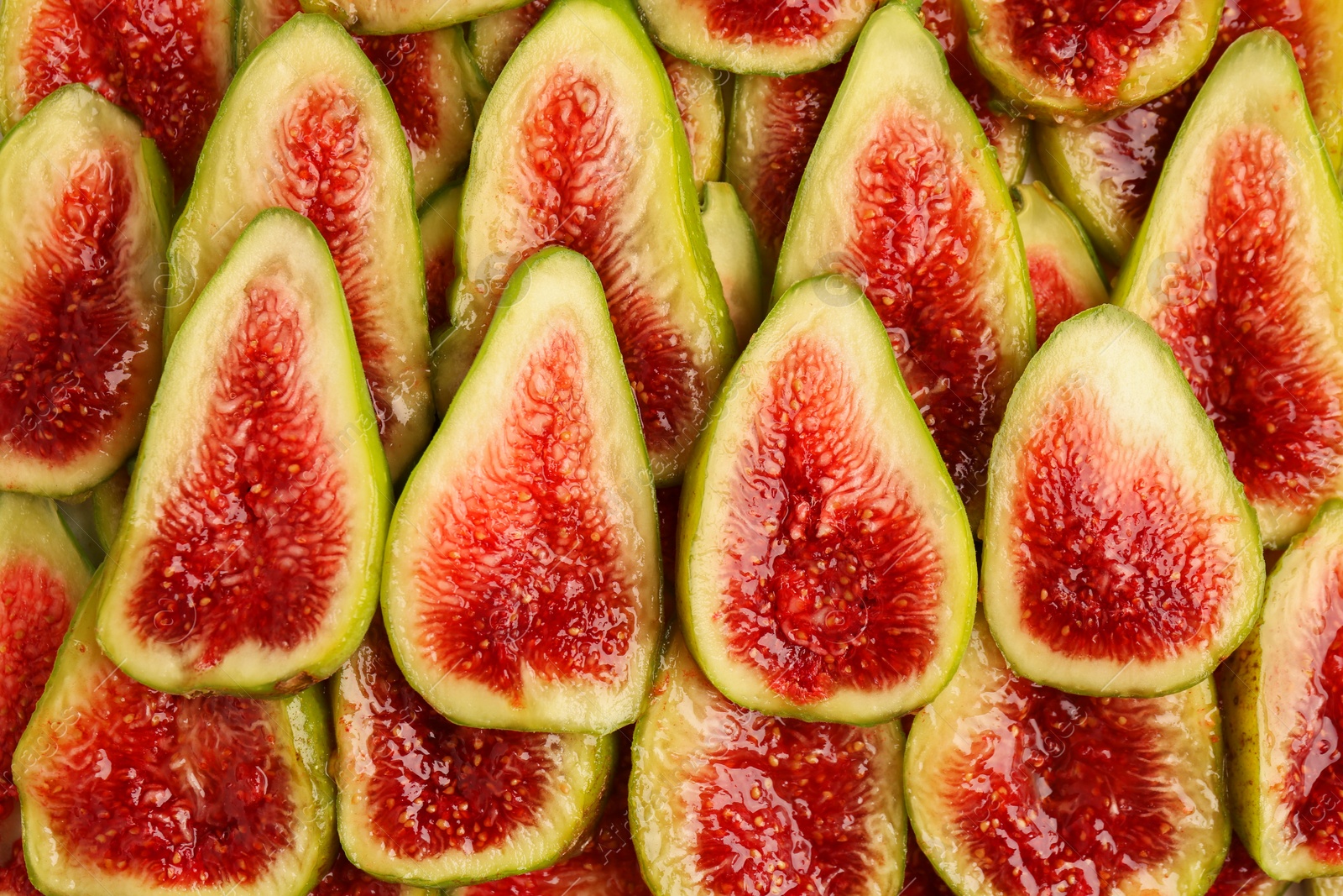 Photo of Pieces of fresh green figs as background, top view