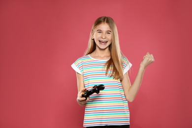 Teenage girl playing video games with controller on color background