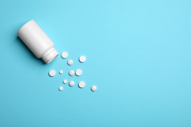 Photo of Container with white pills on color background, flat lay