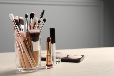 Photo of Set of professional brushes and makeup products on wooden table indoors, space for text