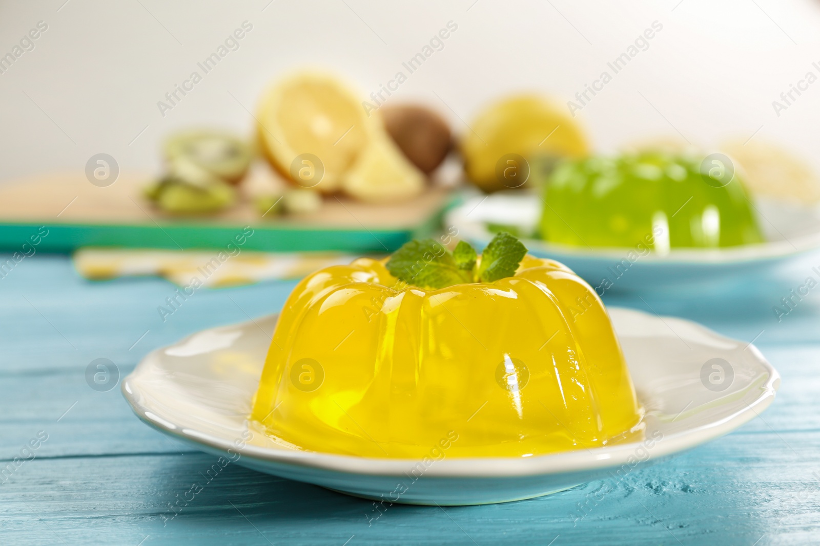 Photo of Plate of tasty fruit jelly on blue wooden table, closeup