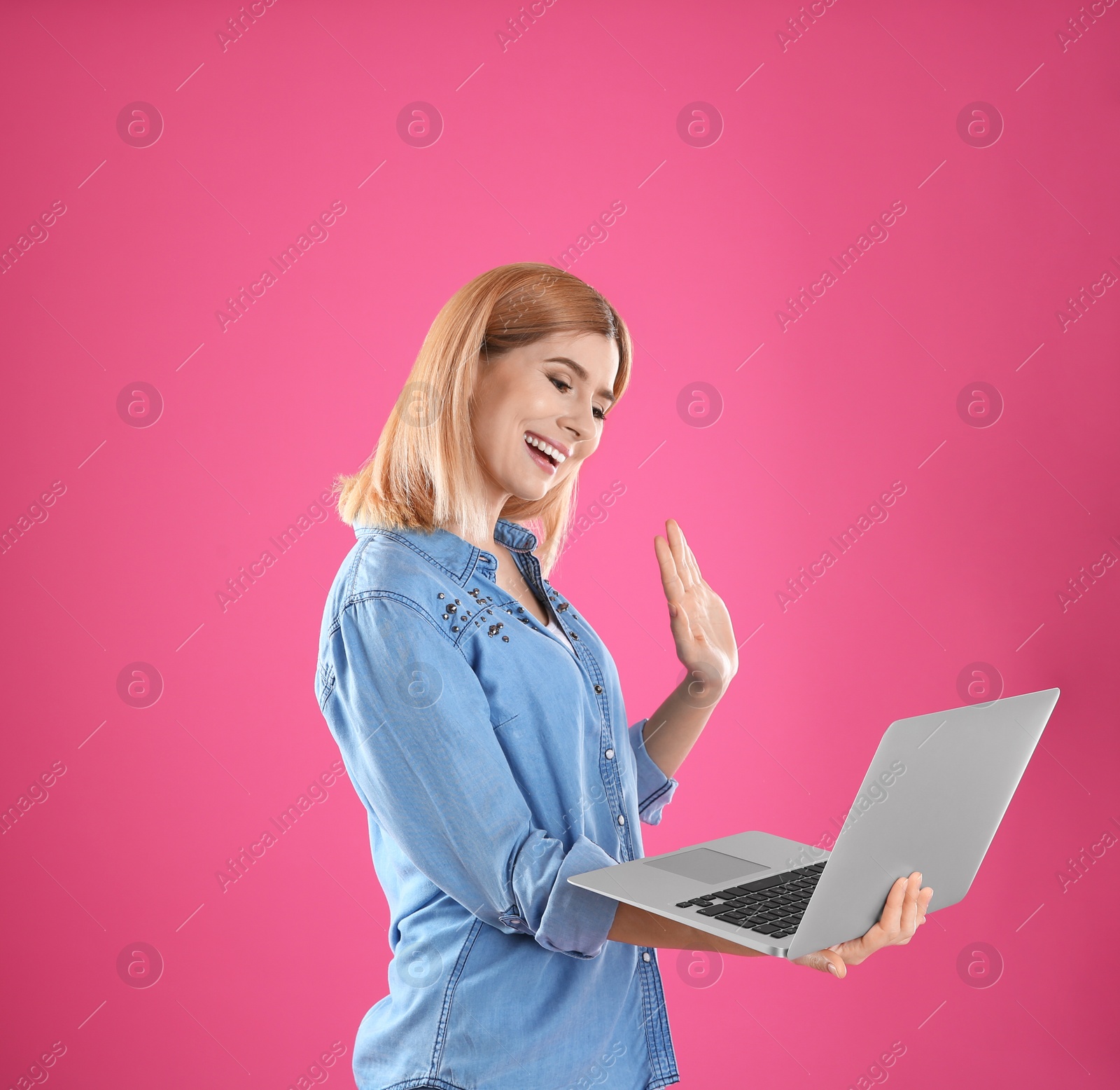 Photo of Woman using laptop for video chat on color background