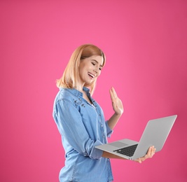 Photo of Woman using laptop for video chat on color background