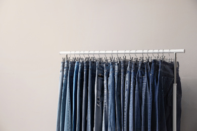 Rack with stylish jeans on beige background