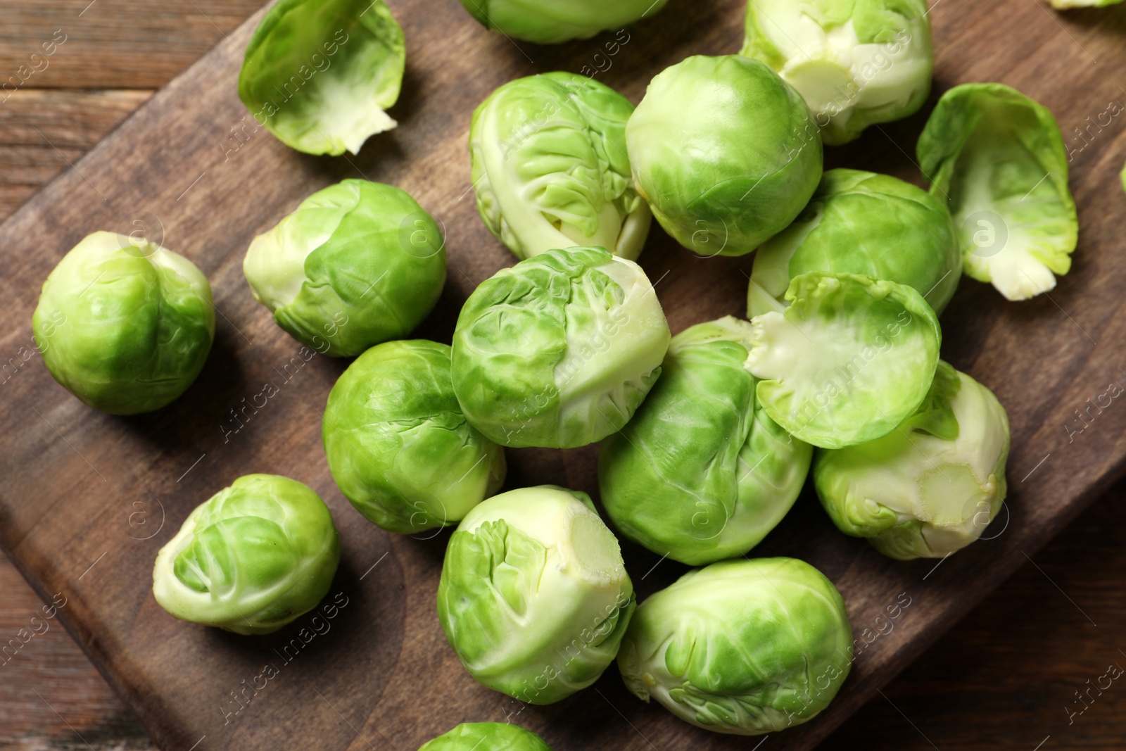 Photo of Board with Brussels sprouts on wooden background, top view