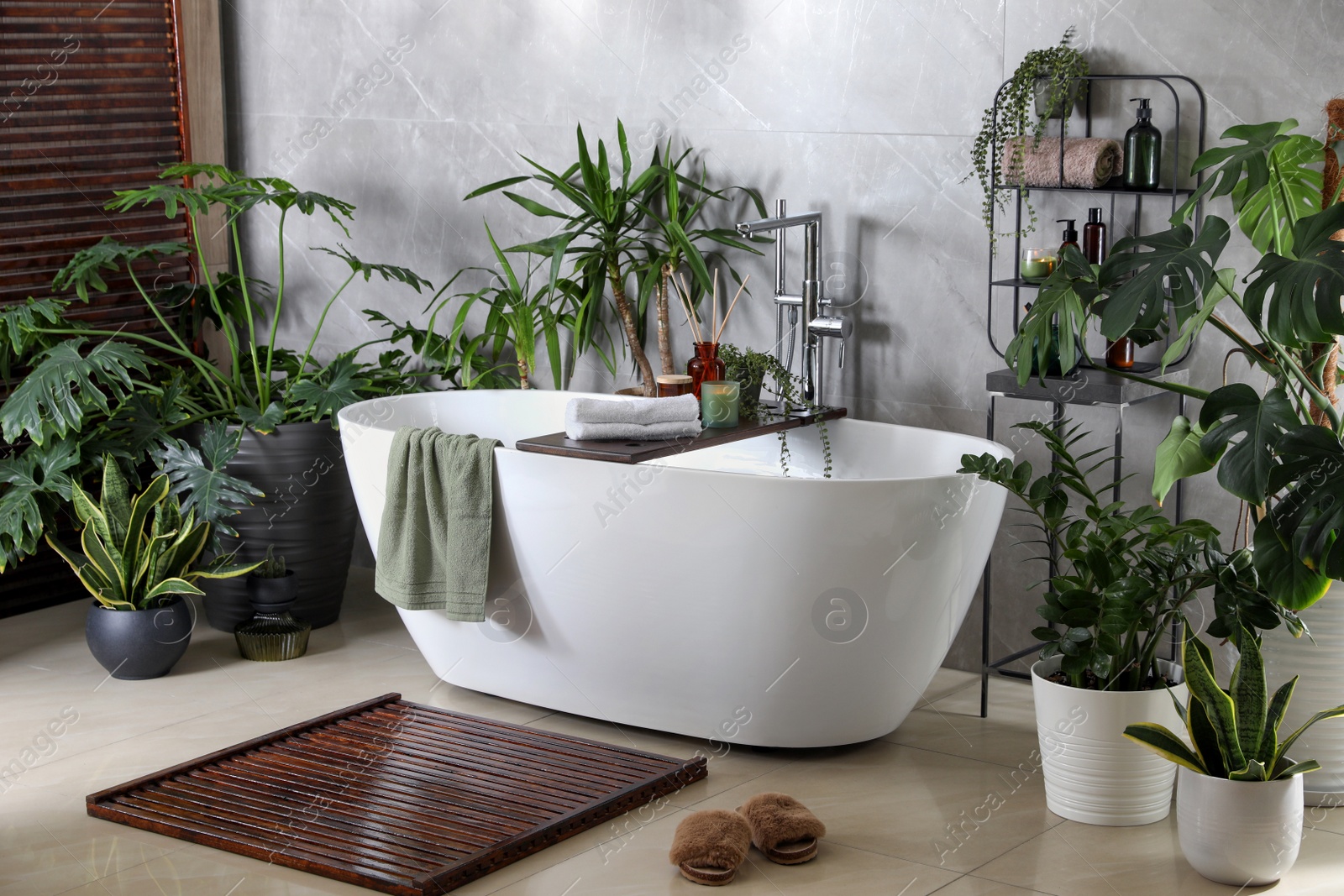 Photo of Modern white tub and beautiful green houseplants in bathroom. Interior design