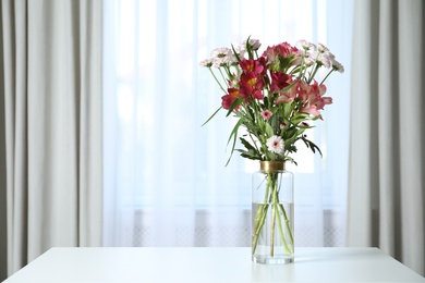 Vase with beautiful flowers on table near window indoors, space for text. Stylish element of interior design