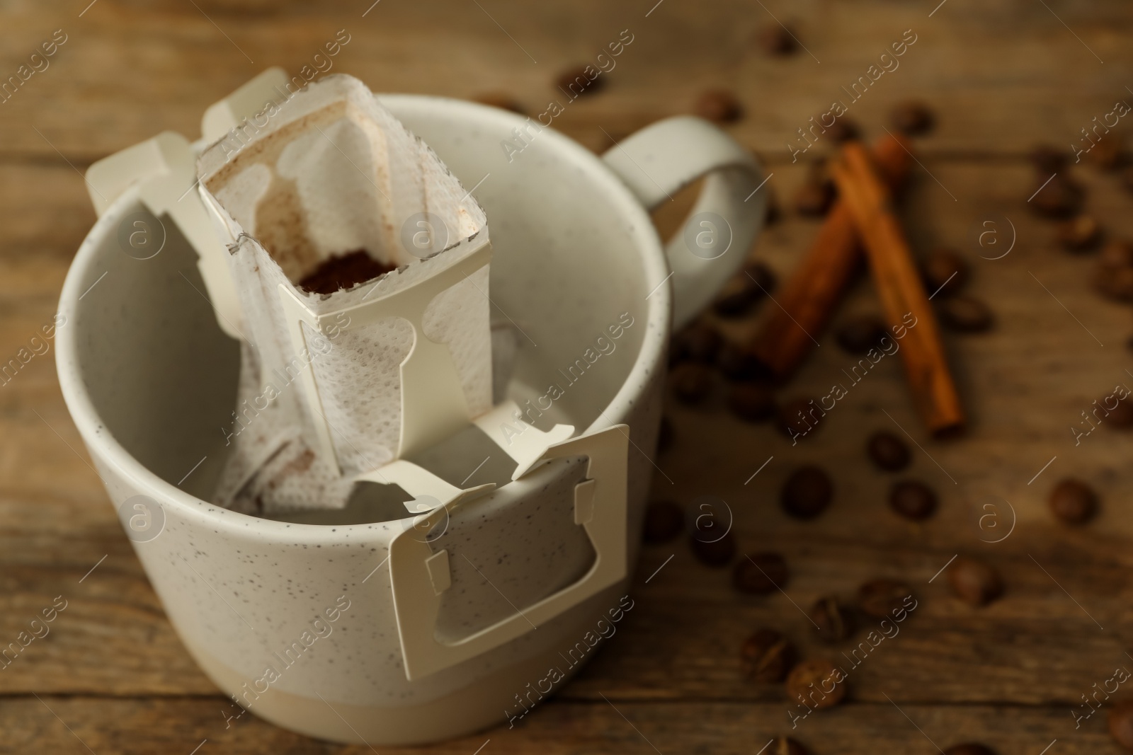 Photo of Drip coffee in cup on wooden table, closeup