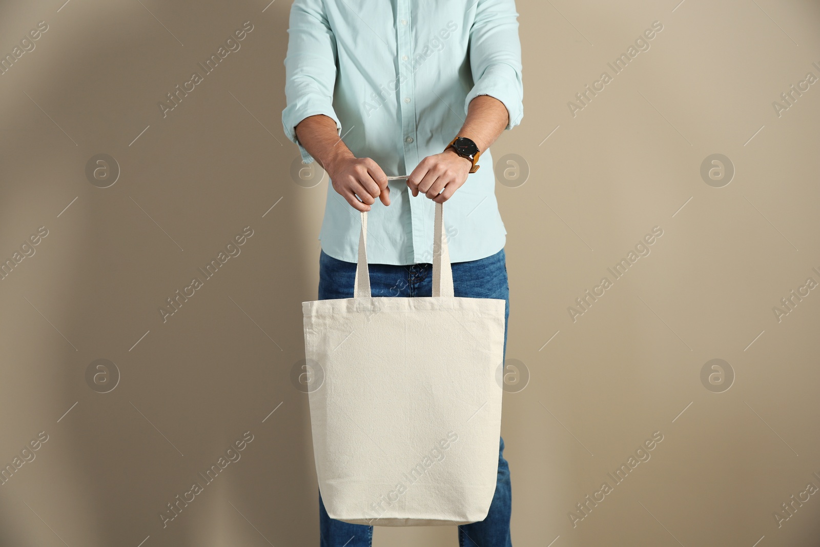 Photo of Young man holding textile bag on color background, closeup. Mockup for design