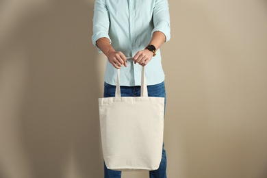 Young man holding textile bag on color background, closeup. Mockup for design