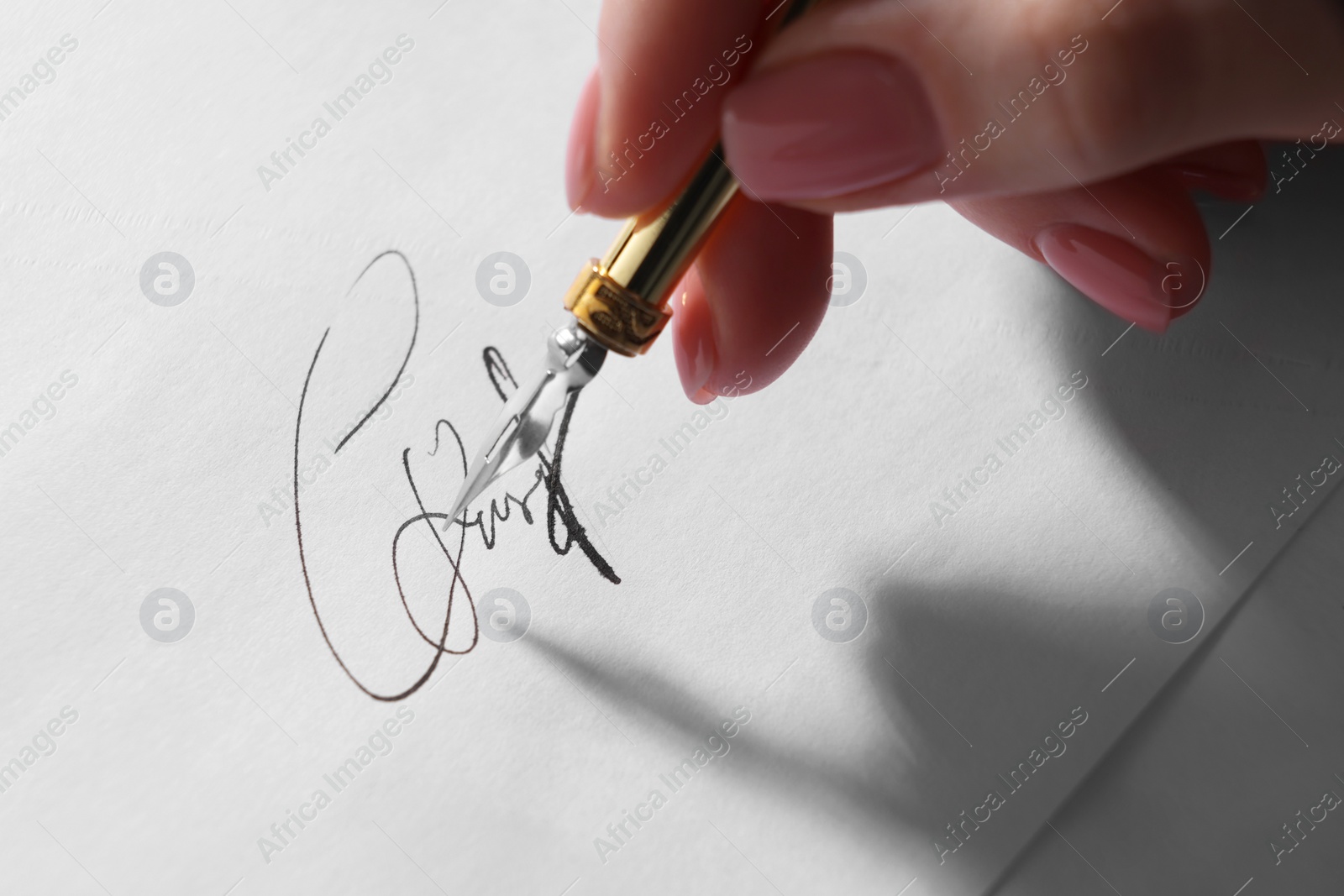 Photo of Woman signing on sheet of paper with fountain pen, closeup