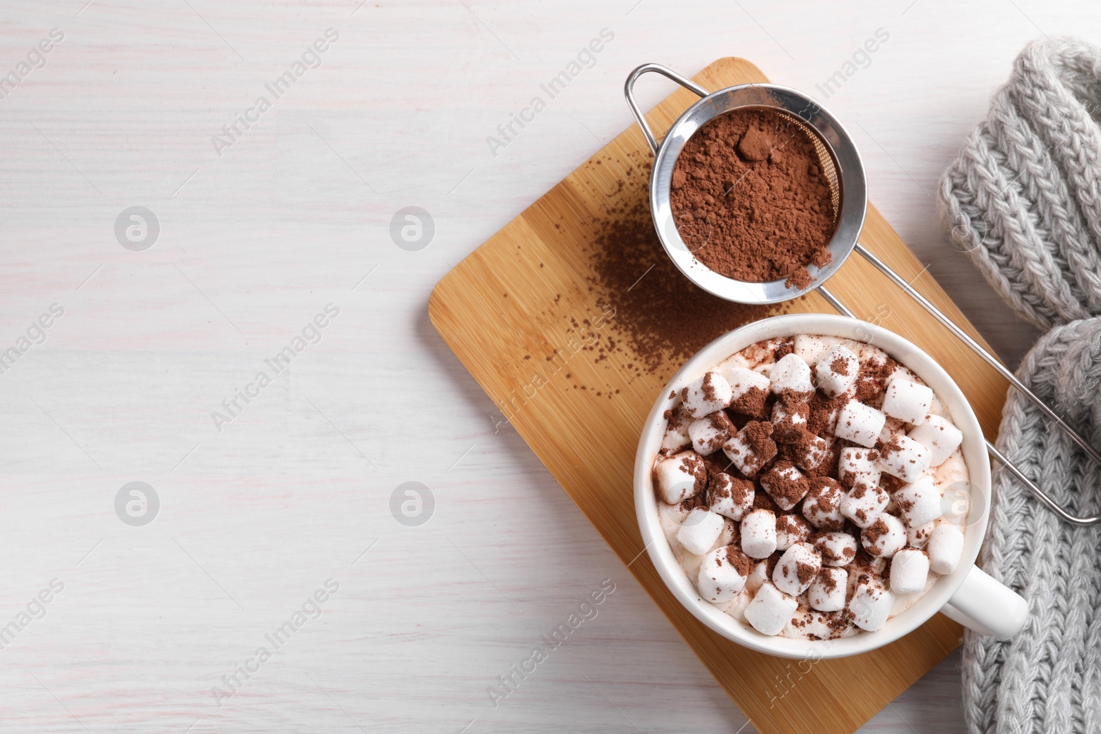 Photo of Cup of aromatic hot chocolate with marshmallows and cocoa powder on light wooden table, top view. Space for text