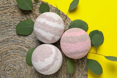 Photo of Bath bombs and eucalyptus leaves on yellow background, flat lay
