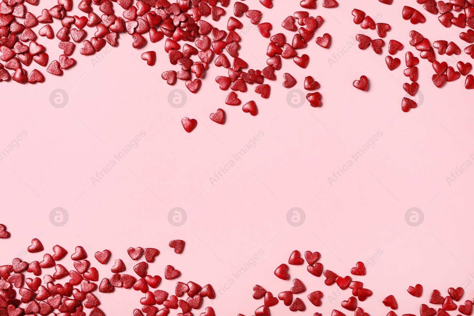 Photo of Red heart shaped sprinkles on pink background, flat lay. Space for text