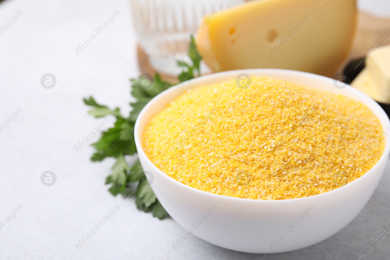 Photo of Raw cornmeal in bowl on light table, closeup. Space for text