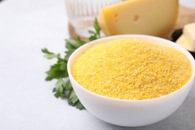 Raw cornmeal in bowl on light table, closeup. Space for text