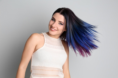 Photo of Young woman with bright dyed hair on light background