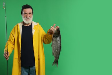 Photo of Fisherman with rod and catch on green background, space for text