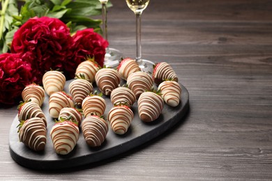 Photo of Delicious chocolate covered strawberries, sparkling wine and flowers on wooden table. Space for text