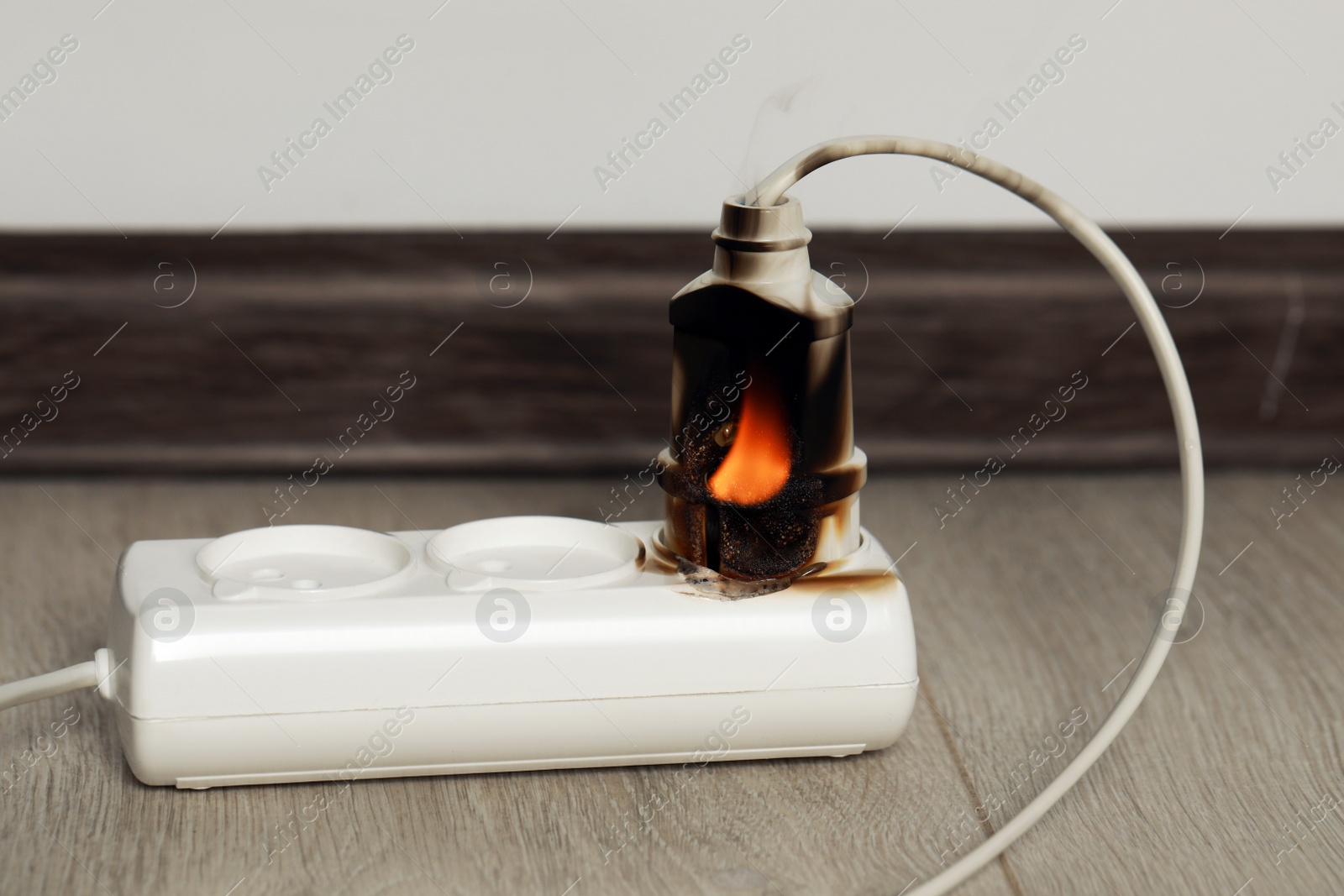 Photo of Inflamed plug in power strip indoors. Electrical short circuit