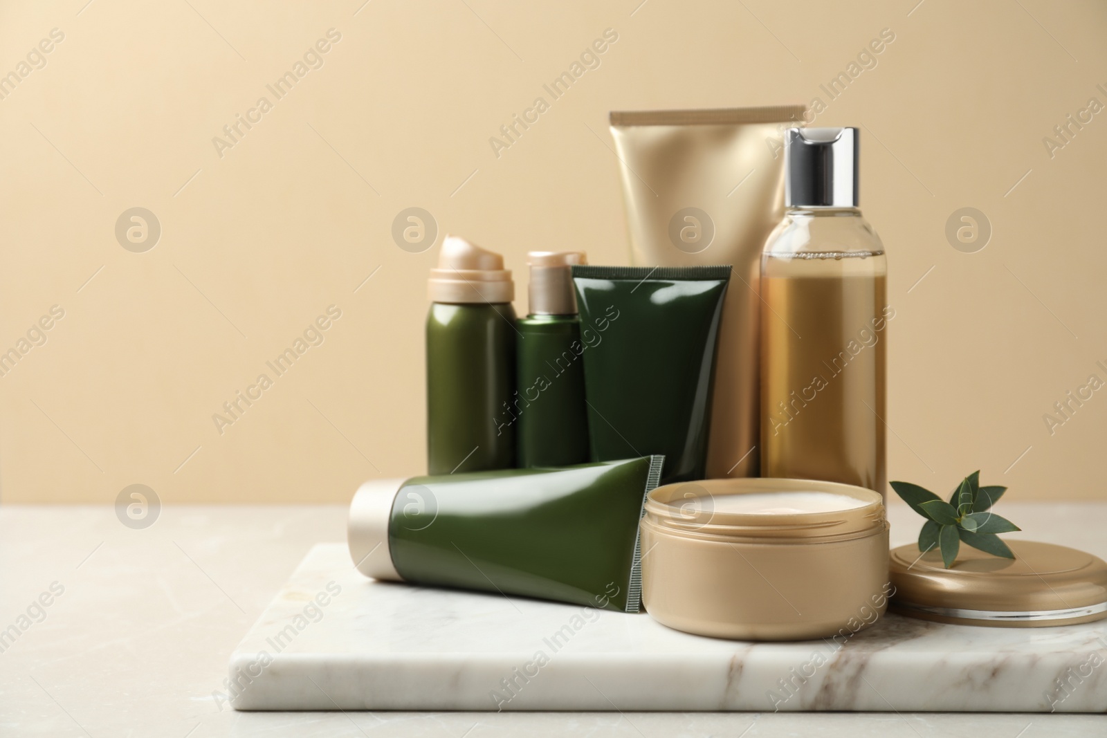 Photo of Different cosmetic products on white table against beige background