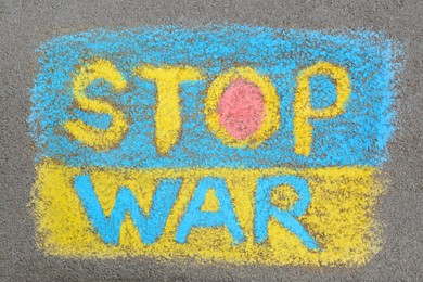 Photo of Ukrainian flag with words Stop War drawn with colorful chalks on asphalt outdoors, top view