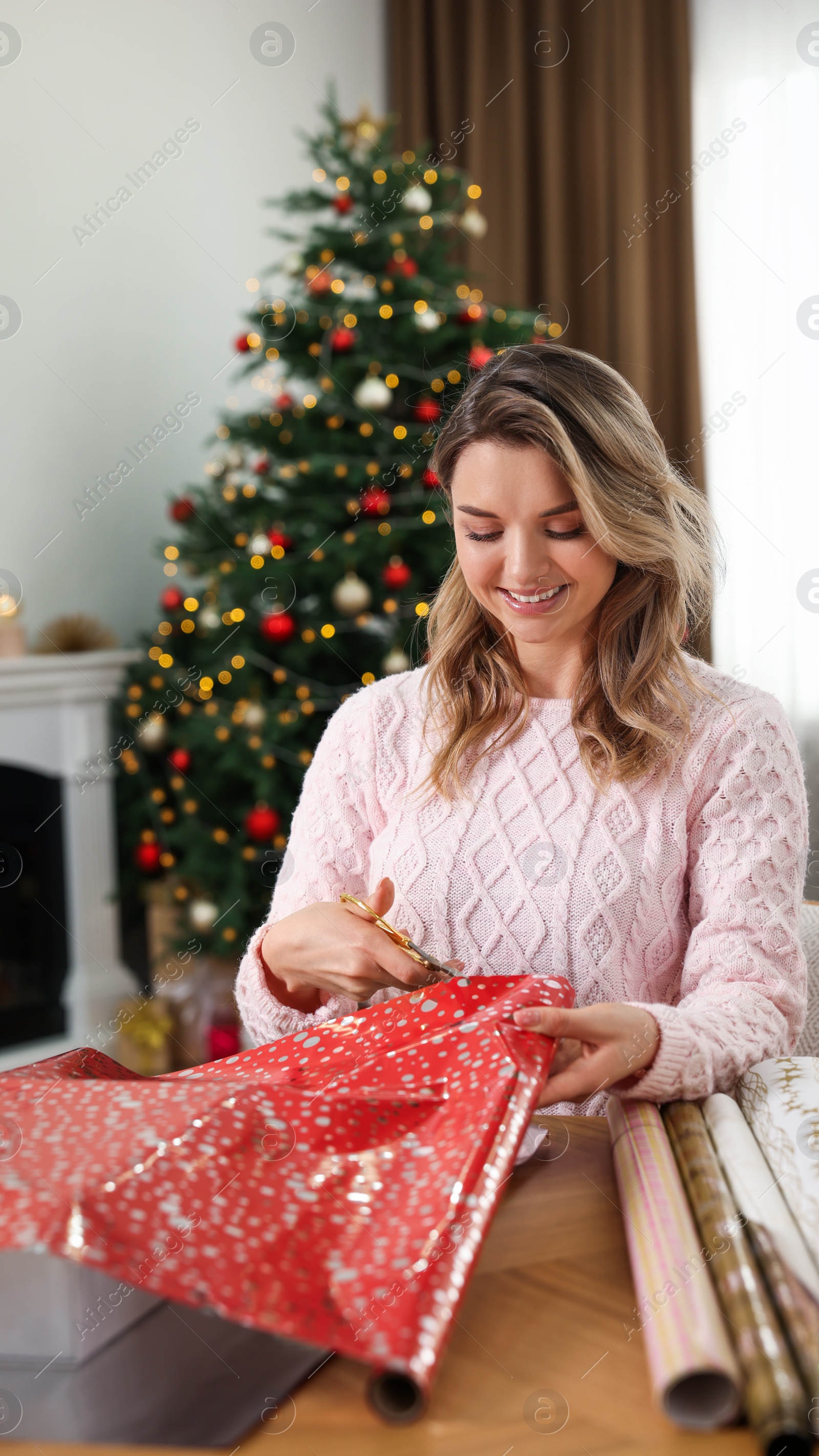 Photo of Beautiful young woman wrapping Christmas gift at home