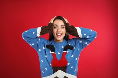 Photo of Young woman in Christmas sweater on red background