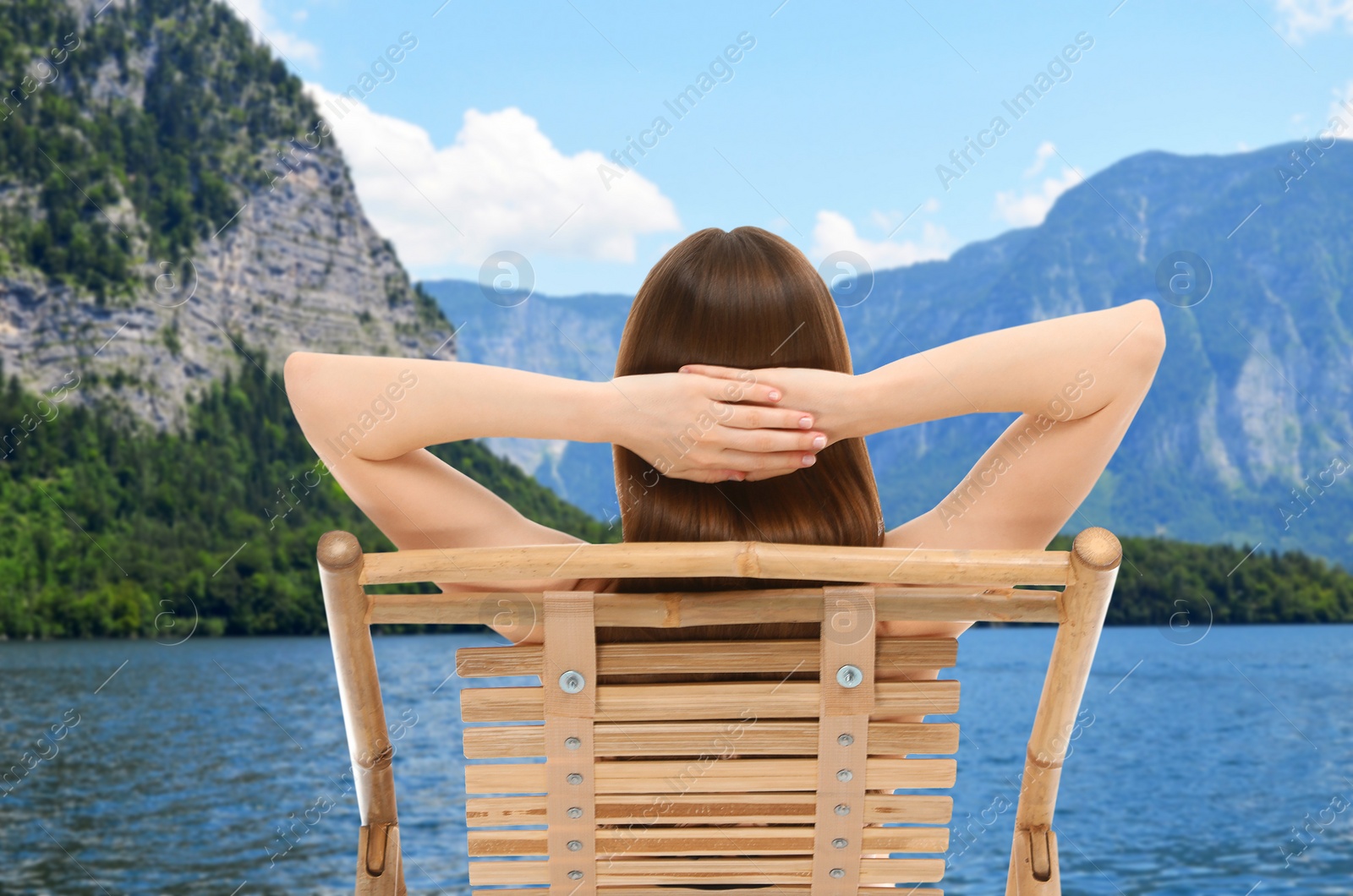 Image of Young woman relaxing on sun lounger near river and mountains. Luxury vacation 