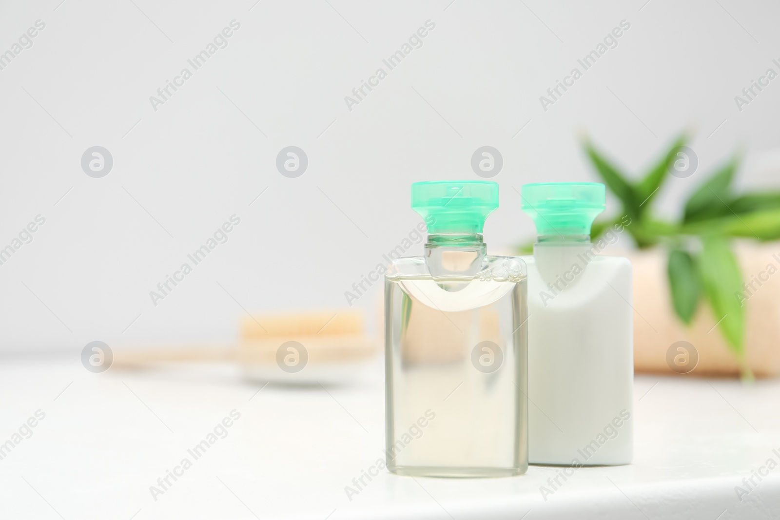 Photo of Mini bottles of cosmetic products on white table against blurred background. Space for text