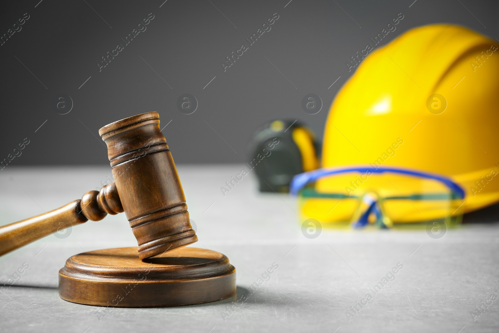 Photo of Construction and land law concepts. Judge gavel, tape measure with hardhat on light grey table, space for text