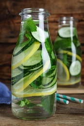 Photo of Refreshing water with cucumber, lemon and mint on wooden table