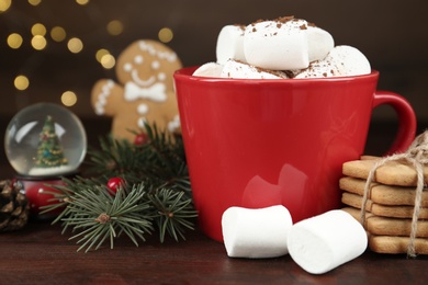Photo of Delicious cocoa drink with marshmallows and Christmas decor on wooden table, closeup