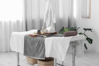 Photo of Rolled towel and spa products on massage table in recreational center