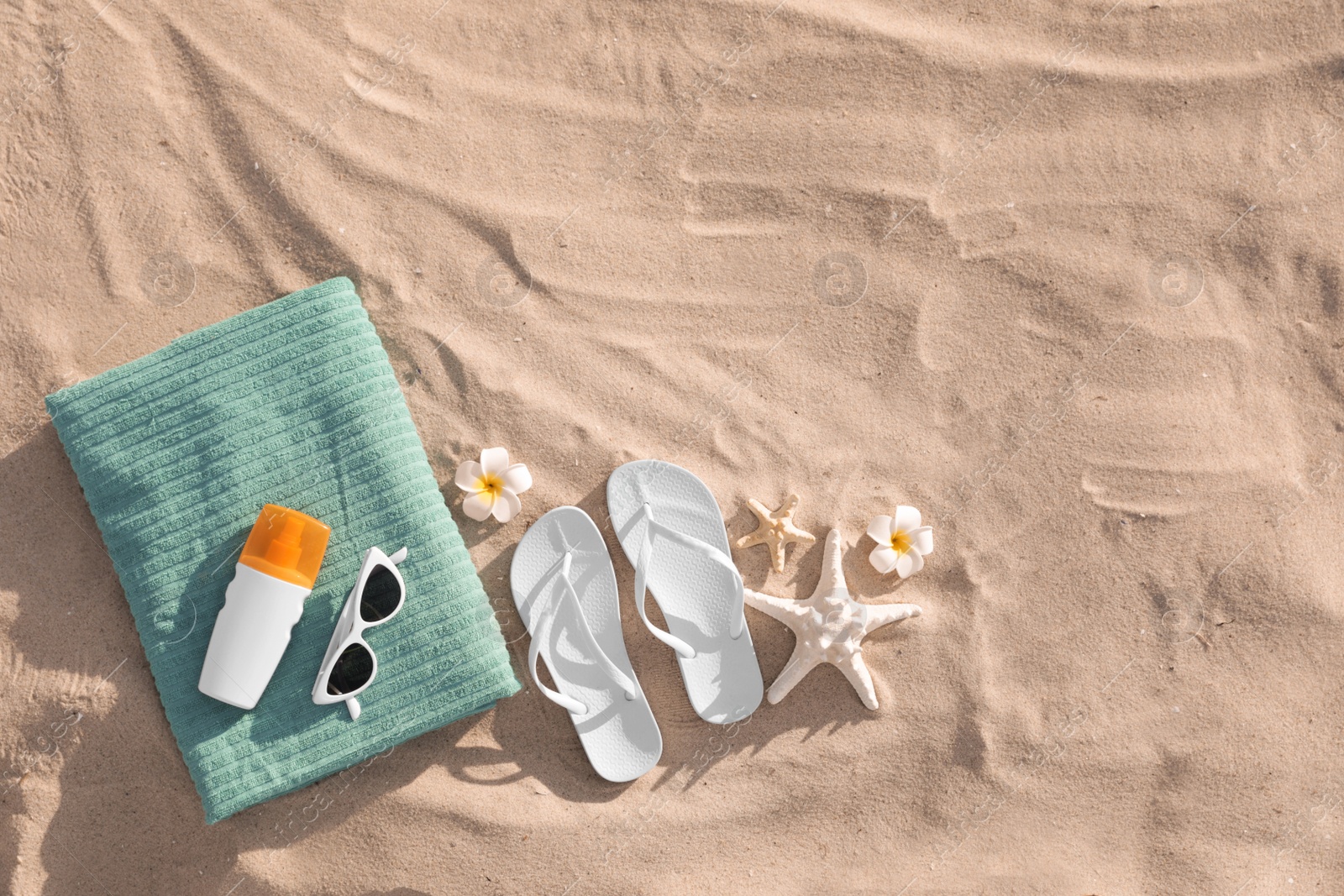 Photo of Flat lay composition with beach accessories on sand. Space for text