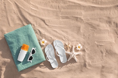 Flat lay composition with beach accessories on sand. Space for text