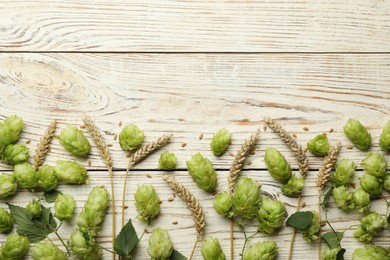 Photo of Flat lay composition with fresh green hops and wheat ears on white wooden table, space for text