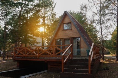 Picturesque view of modern wooden house with veranda near forest on sunny day