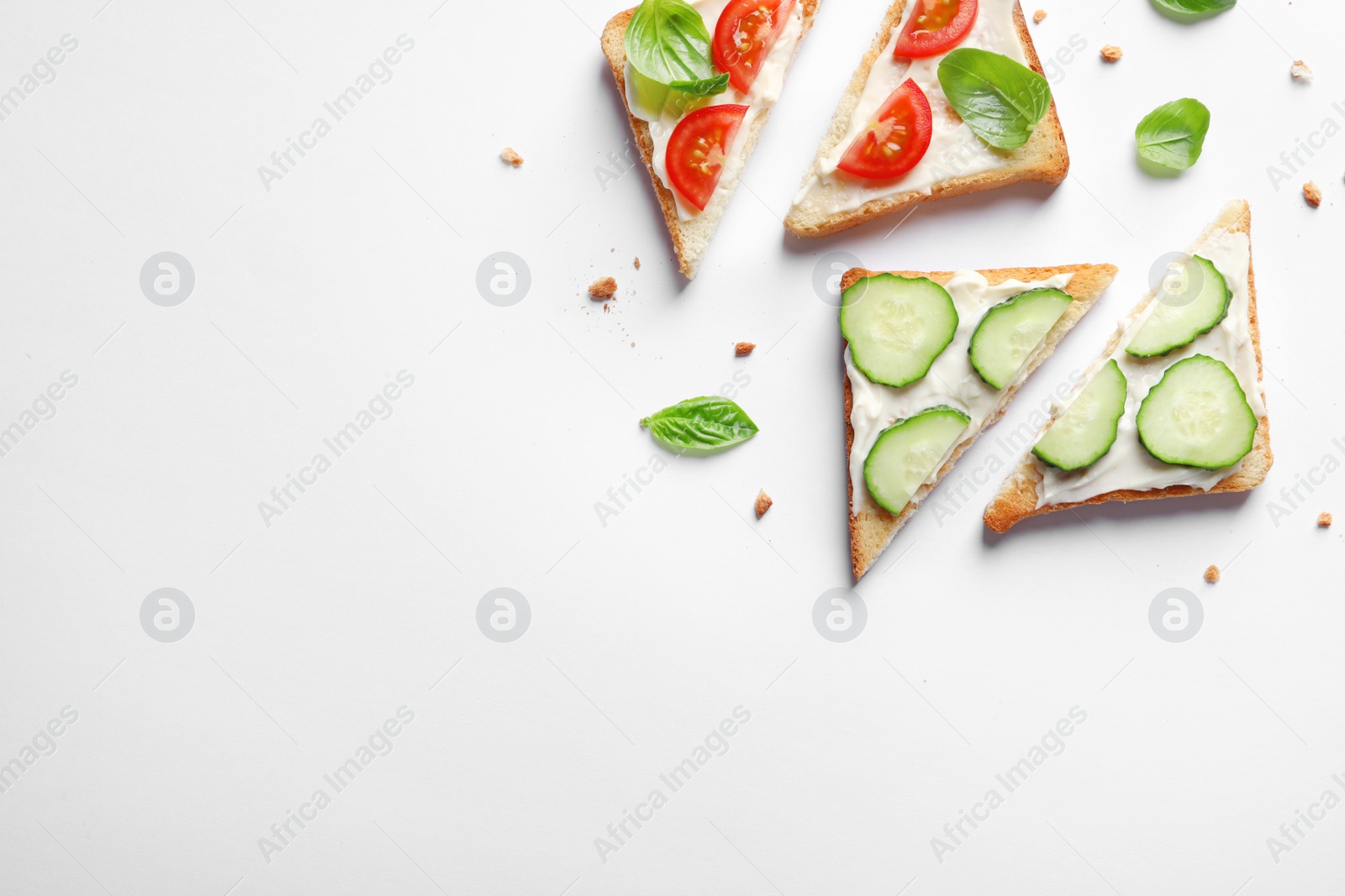 Photo of Tasty toast bread with cream cheese, cucumbers and cherry tomatoes on white background