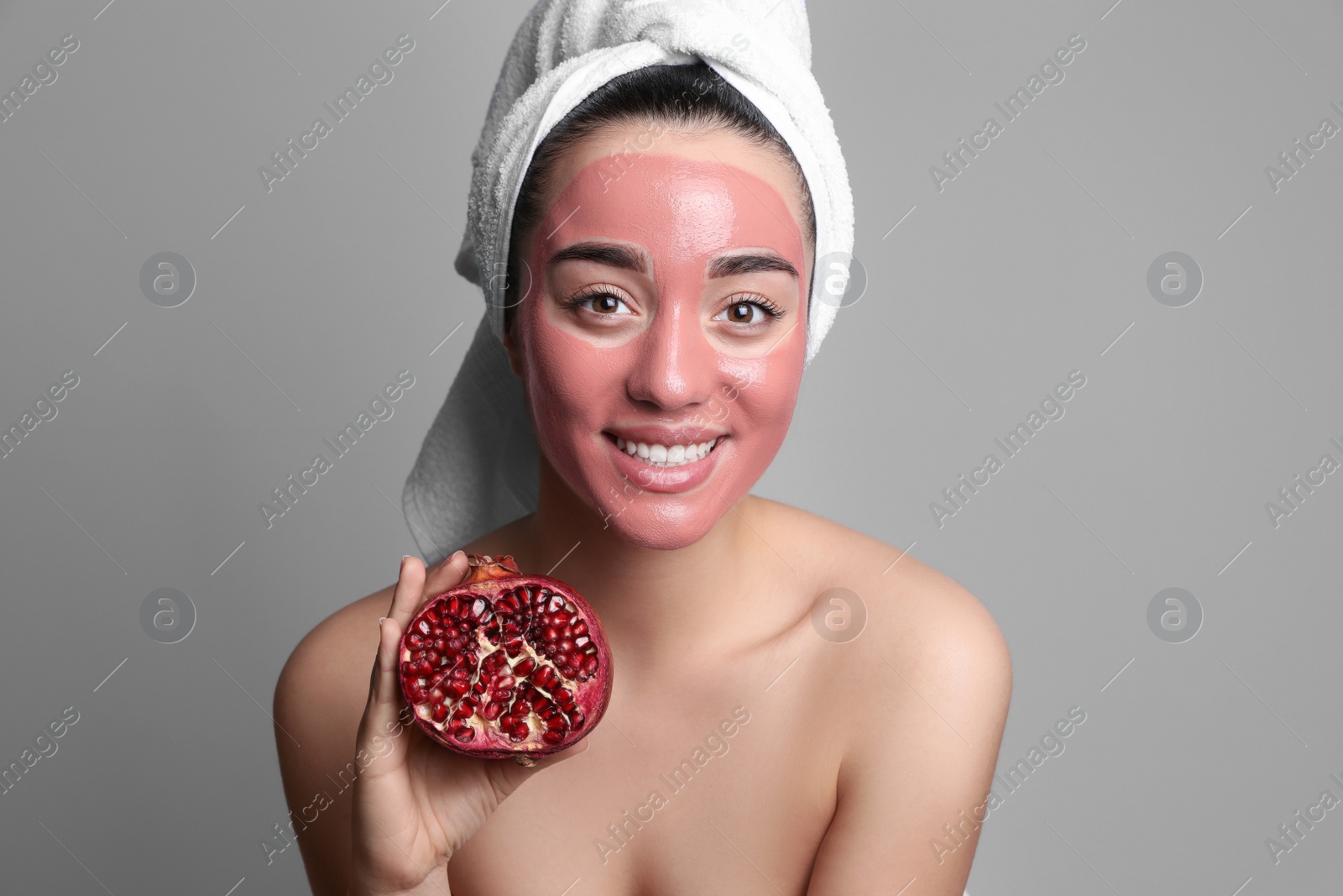 Photo of Woman with pomegranate face mask and fresh fruit on grey background