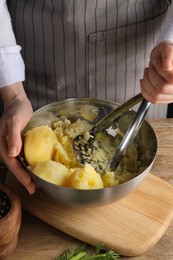 Photo of Woman making mashed potato at wooden table, closeup