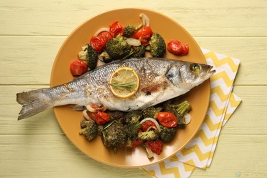 Photo of Delicious baked fish and vegetables on yellow wooden table, top view