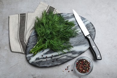 Photo of Marble board with fresh green dill, knife and spices on grey table, flat lay