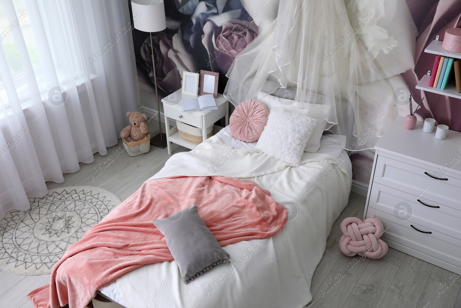 Photo of Teenage girl's room interior with comfortable bed and floral wallpaper. Idea for stylish design