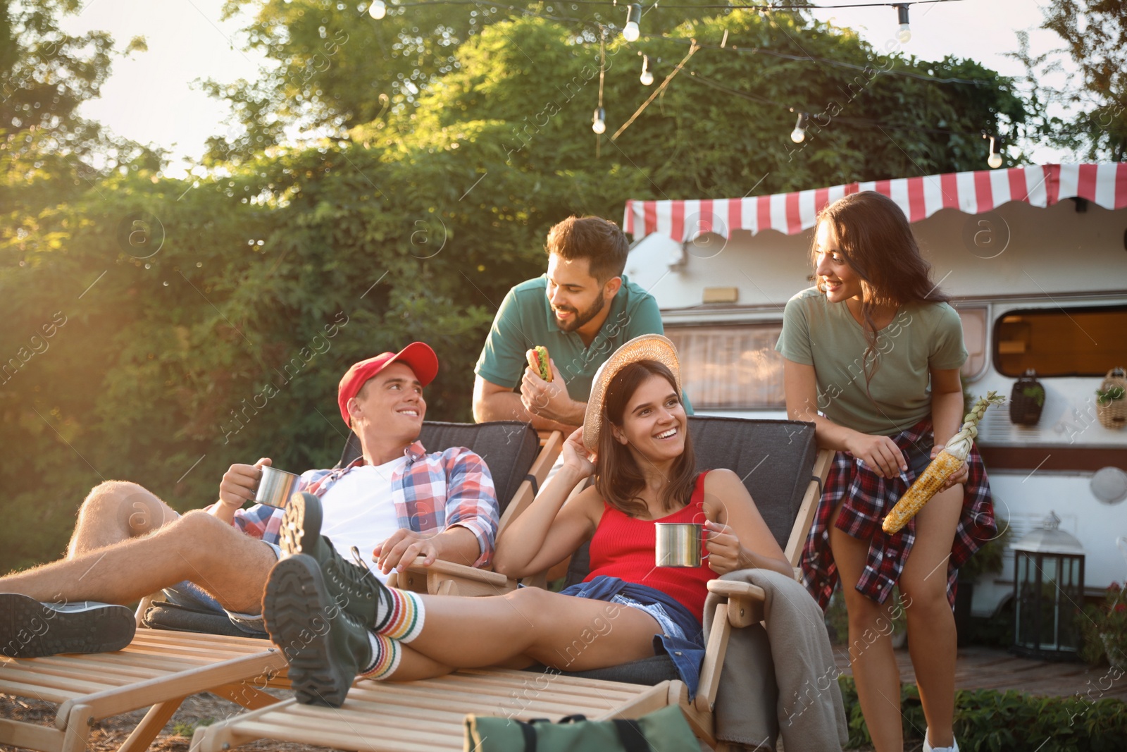 Photo of Happy friends resting near motorhome. Camping season