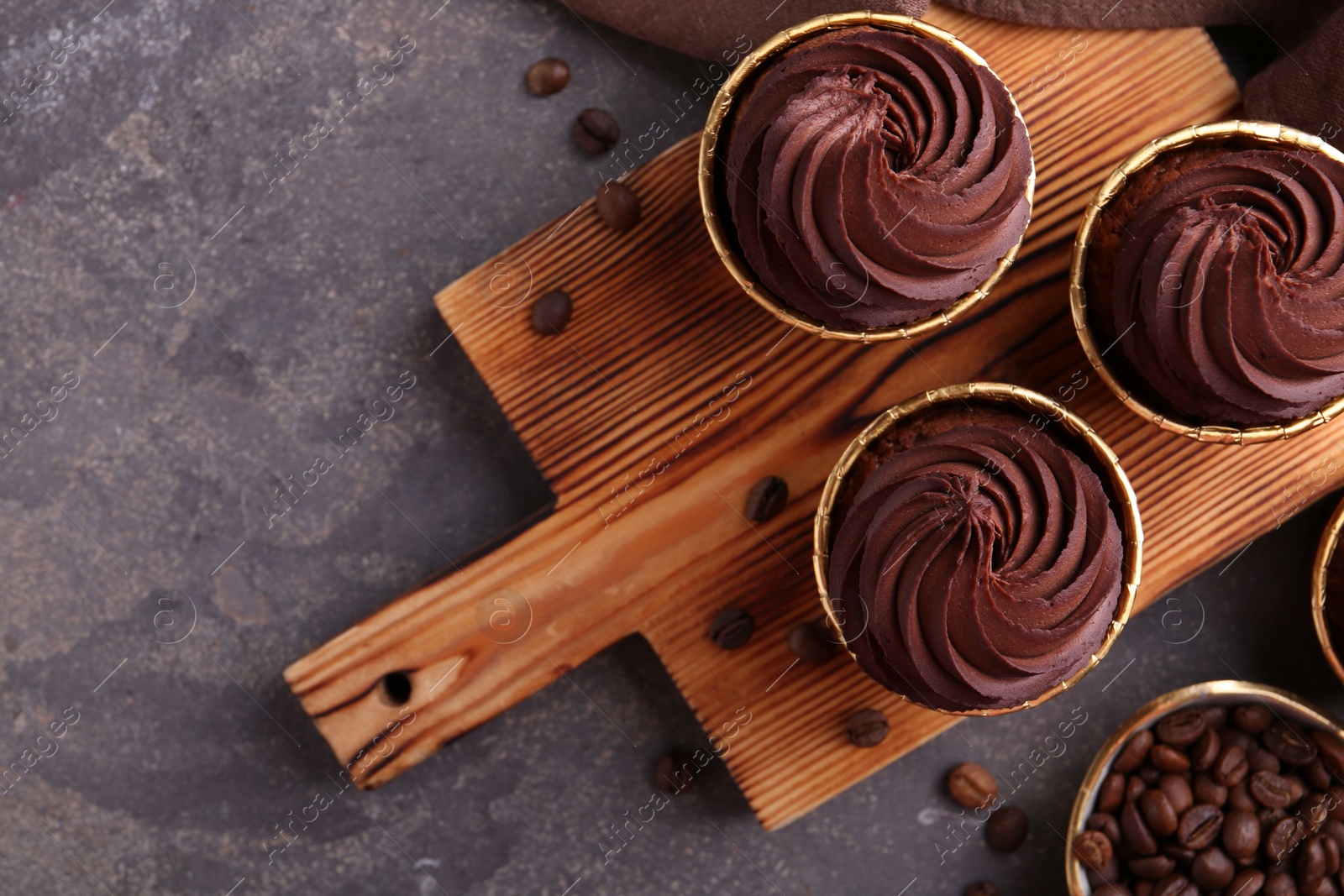 Photo of Delicious chocolate cupcakes and coffee beans on grey textured table, flat lay