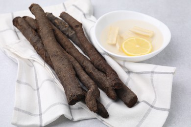 Raw salsify roots and bowl with lemon on white table